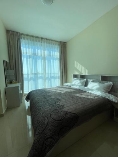 a bedroom with a bed and a large window at Lovely 2 BHK just 2 min from the beach in Ajman 