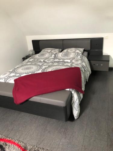 a bedroom with a bed with a red blanket at À proximité de Strasbourg in Kilstett