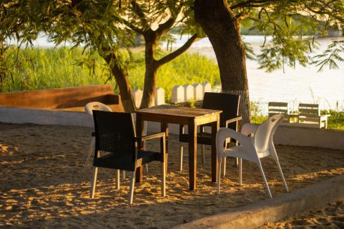 Captains Villa - where Lake Malawi and Shire River meet, historical hotel at waterfront next to the Lake Museum in Mangochi Town في Mponda: طاولة وكراسي يجلسون بجوار شجرة