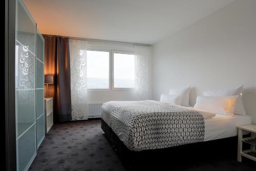 a white bedroom with a bed and a window at FourSide Plaza Hotel Trier, Trademark Collection by Wyndham in Trier