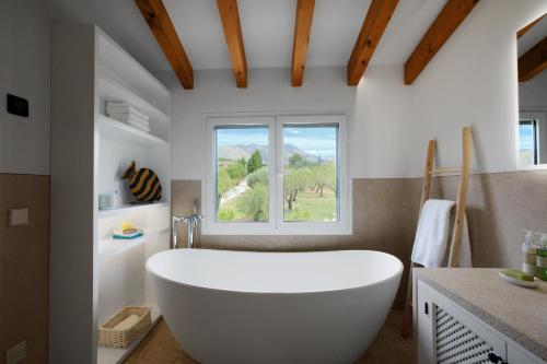 baño con bañera blanca y ventana en Ca Na Bennassar Pollensa - BY EMERALD STAY en Pollensa
