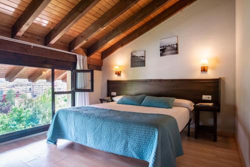 a bedroom with a large bed and a large window at Apartamentos Aldea del Puente in Cangas de Onís