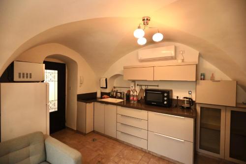 La cuisine est équipée de placards blancs et d'un réfrigérateur blanc. dans l'établissement St. John Apartment, à Jérusalem