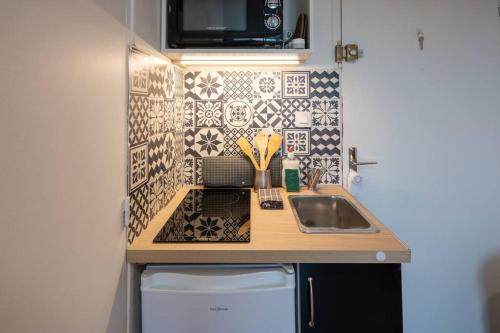 une petite cuisine avec un évier et une cuisinière dans l'établissement Le pragmatique, à Évreux