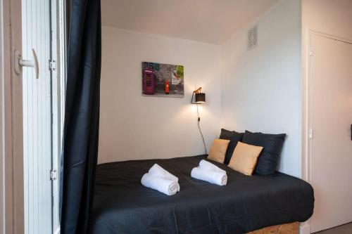 Schlafzimmer mit einem schwarzen Bett und weißen Kissen in der Unterkunft Le pragmatique in Évreux