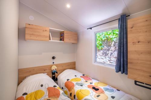 2 camas en una habitación pequeña con ventana en Mobile-home Baia, en Saint-Raphaël
