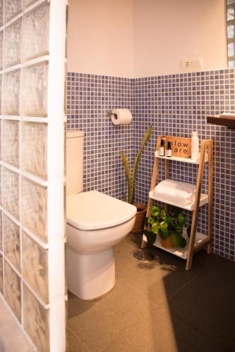 a bathroom with a toilet and a blue tiled wall at Slow Axarquía in Torre de Benagalbón