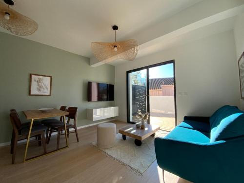 a living room with a blue couch and a table at Les Loges de la Mer - Pérols in Pérols
