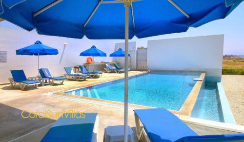 a swimming pool with blue chairs and umbrellas at Blue - Beach Front Spectacular Villa Sleeps 10 in Argaka