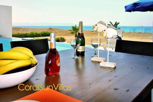 a wooden table with bottles and glasses of wine at Blue - Beach Front Spectacular Villa Sleeps 10 in Argaka