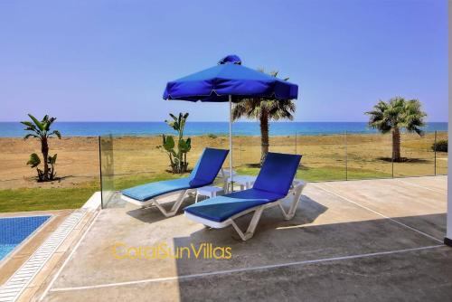 two chairs and an umbrella next to the beach at Blue - Beach Front Spectacular Villa Sleeps 10 in Argaka