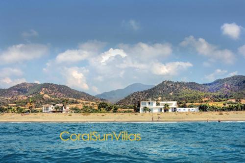 a beach with houses and mountains in the background at Blue - Beach Front Spectacular Villa Sleeps 10 in Argaka
