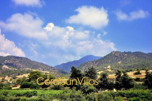 a view of a mountain range with clouds in the sky at Blue - Beach Front Spectacular Villa Sleeps 10 in Argaka
