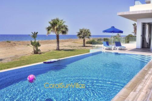 a swimming pool with a beach in the background at Blue - Beach Front Spectacular Villa Sleeps 10 in Argaka