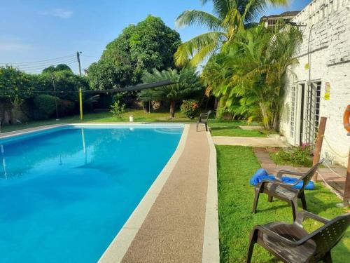 a swimming pool with two chairs next to a house at casa con piscina aeropuerto flandes in Flandes