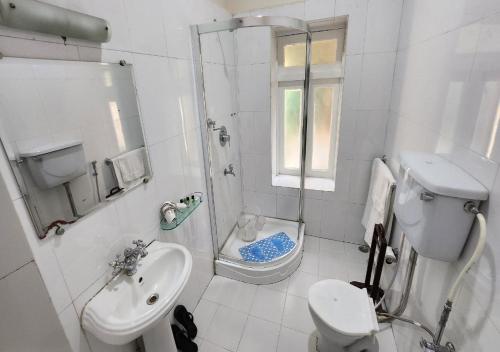 a white bathroom with a toilet and a sink at Ivanhoe Hotel (A Heritage Property) in Darjeeling