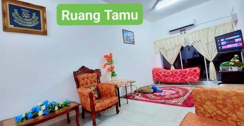 ein Wohnzimmer mit einem Sofa, einem Stuhl und einem TV in der Unterkunft Homestay Intan Anjung Lodge in Malakka