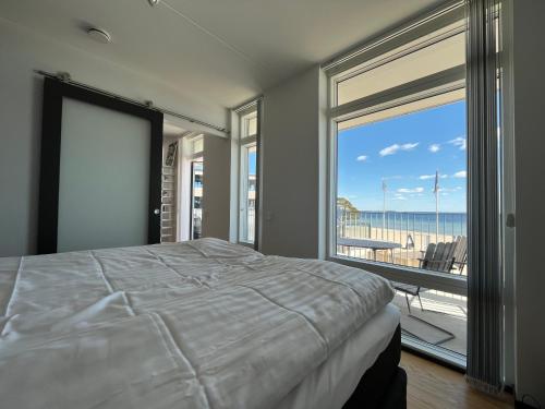 een slaapkamer met een bed en uitzicht op het strand bij ÅhusBrygga Apartment Hotel in Åhus