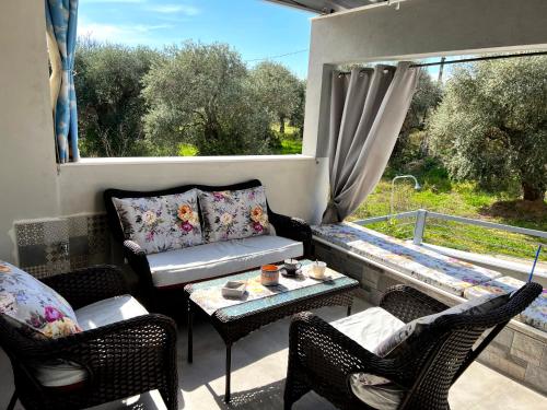 uma varanda com um sofá, cadeiras e uma mesa em Villa Stemily em Skala Rachoniou