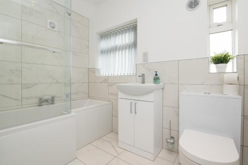 a white bathroom with a tub and a toilet and a sink at Super King Bed Free Parking Alexa Garden Patio BBQ Sleeps 6 in Avonmouth