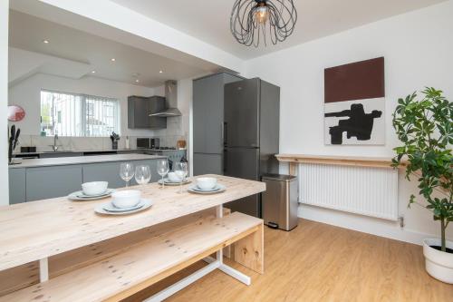 a kitchen with a wooden table with wine glasses at Super King Bed Free Parking Alexa Garden Patio BBQ Sleeps 5 in Avonmouth