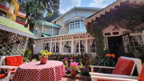 a table and chairs in front of a house with flowers at Ivanhoe Hotel (A Heritage Property) in Darjeeling