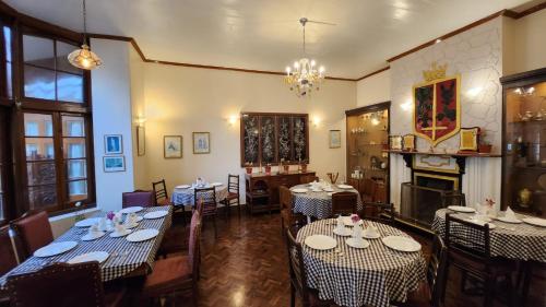 a dining room with tables and chairs and a fireplace at Ivanhoe Hotel (A Heritage Property) in Darjeeling