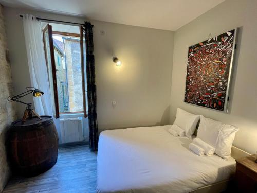 a bedroom with a white bed and a painting on the wall at Maison d'Artiste dans le Coeur Historique in Sarlat-la-Canéda