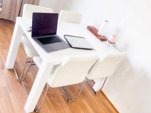 un computer portatile seduto su un tavolo bianco con sedie bianche di Ilona Apartments -"Home Away From Home" a Kotka
