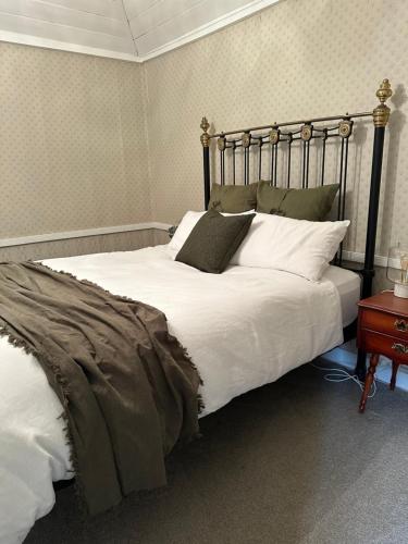 a bedroom with a large bed with white sheets and pillows at Ulva Cottage - Historical BnB in Penola