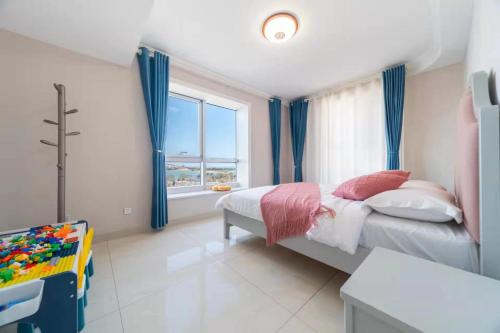 um quarto com uma cama com cortinas azuis e uma janela em Cloud & Sea Boutique Apartment em Rizhao