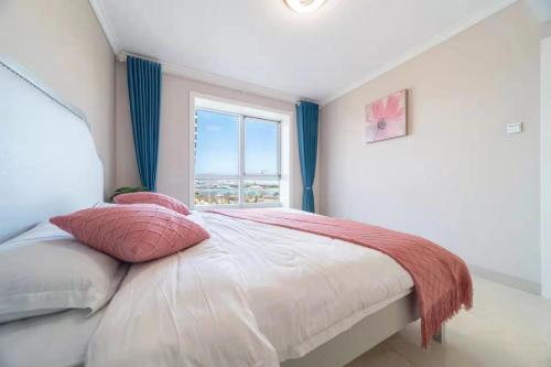 a bedroom with a large bed with a window at Cloud & Sea Boutique Apartment in Rizhao