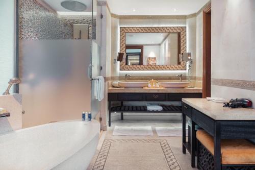 a bathroom with a tub and a sink and a mirror at Banana Island Resort Doha by Anantara in Doha