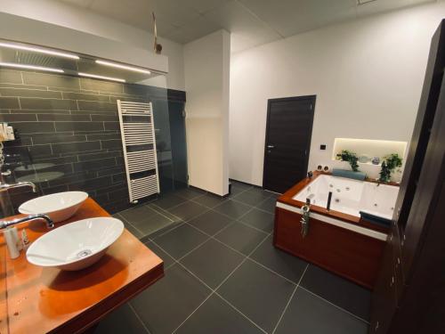 een badkamer met 2 wastafels en een bad bij De Wellnessloft Bocholt in Bocholt