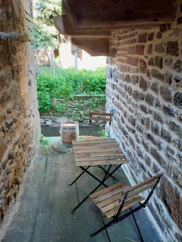 two benches sitting next to a brick wall at Le petit atelier, centre-ville, vue rivière in Villedieu-les-Poëles