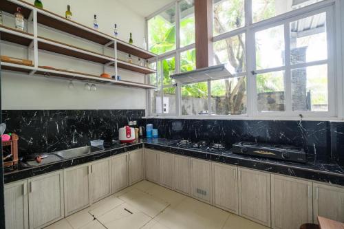 Una cocina con encimeras y ventanas de mármol negro. en Puri Gading Villa Jimbaran by The Lavana - 5 Bedroom Villa, en Jimbaran