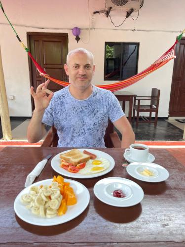 Un uomo seduto a un tavolo con piatti di cibo di Romance in Bey ad Arugam