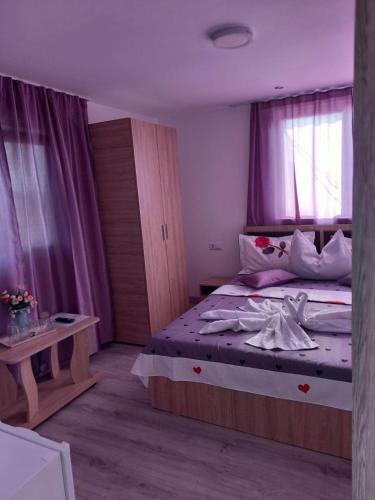 ein Schlafzimmer mit einem großen Bett mit lila Vorhängen in der Unterkunft Casa IOANA Corbu in Corbu