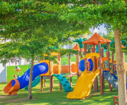 um parque infantil com escorregas coloridos e árvores num parque em Mavsa Resort em Cesário Lange