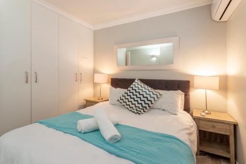 a bedroom with a bed with two lamps and a mirror at Chaka's Cove 66 in Ballito
