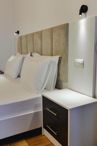 a white bed with white pillows and a night stand at Venti et Maris in Ksamil