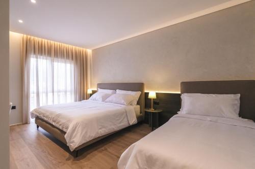 a hotel room with two beds and a window at Two Steps Apartments Tirana in Tirana