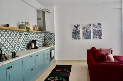 eine Küche mit blauen Schränken und einem roten Stuhl in der Unterkunft Lovely 2 bedroom condo with free parking in Vlorë