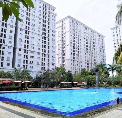 a large swimming pool in front of tall buildings at Apartment Kalibata City by PanBul in Jakarta