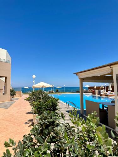 a resort with a swimming pool and tables and chairs at Nautica Hotel Apartments in Stavromenos