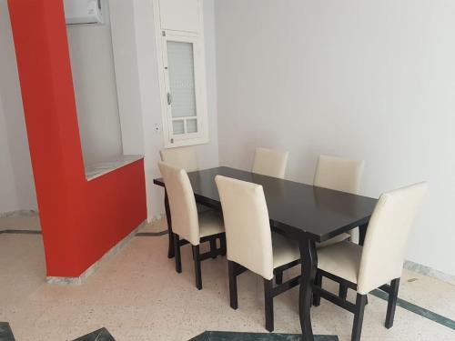 ein Esszimmer mit einem schwarzen Tisch und weißen Stühlen in der Unterkunft Djerba La Douce in Houmt Souk