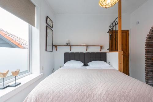 een slaapkamer met een groot bed en een raam bij La Chatelaine in Egmond aan Zee