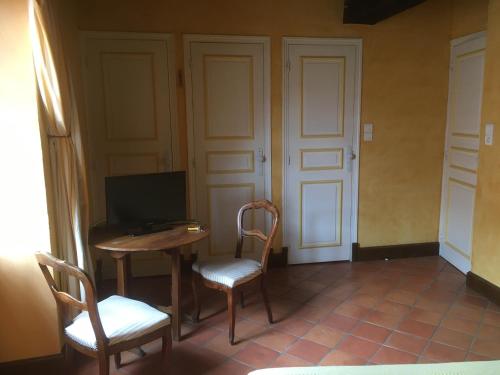 una stanza con tavolo, due sedie e televisore di Au temps d'Autrefois a Nolay