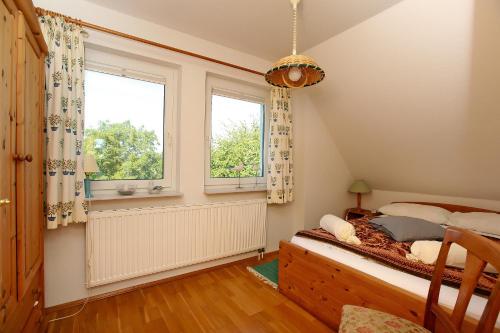 - une chambre avec un lit et 2 fenêtres dans l'établissement Ferienhaus Uli, à Wustrow