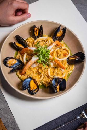 a plate of food with mussels and noodles on a table at Skiathos Thalassa Cape Hotel, Philian Hotels and Resorts in Megali Ammos